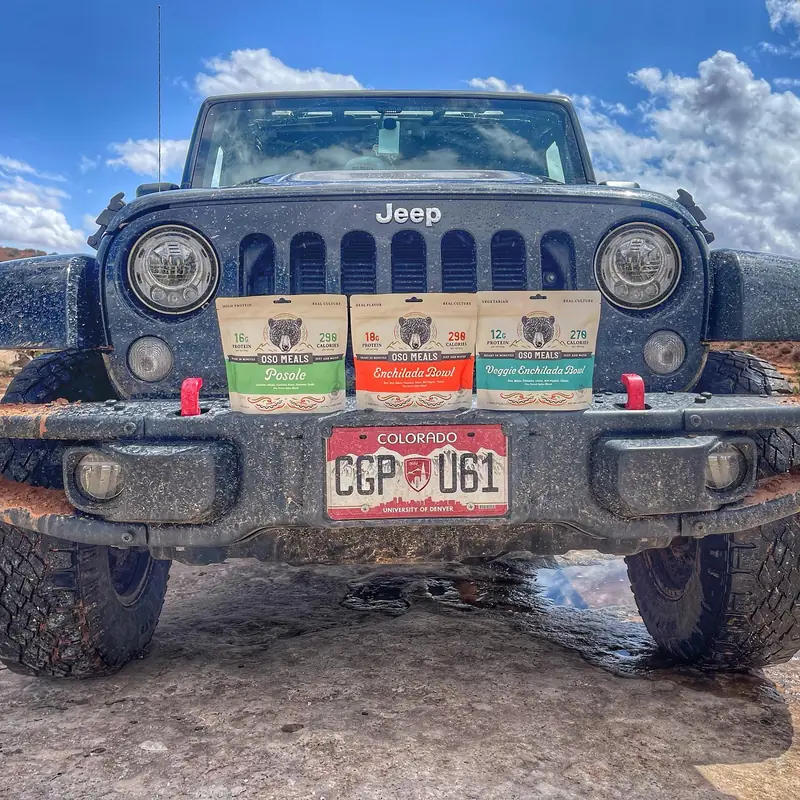 Three Oso pouches lined up on the bumper of a muddy Jeep with Colorado plates